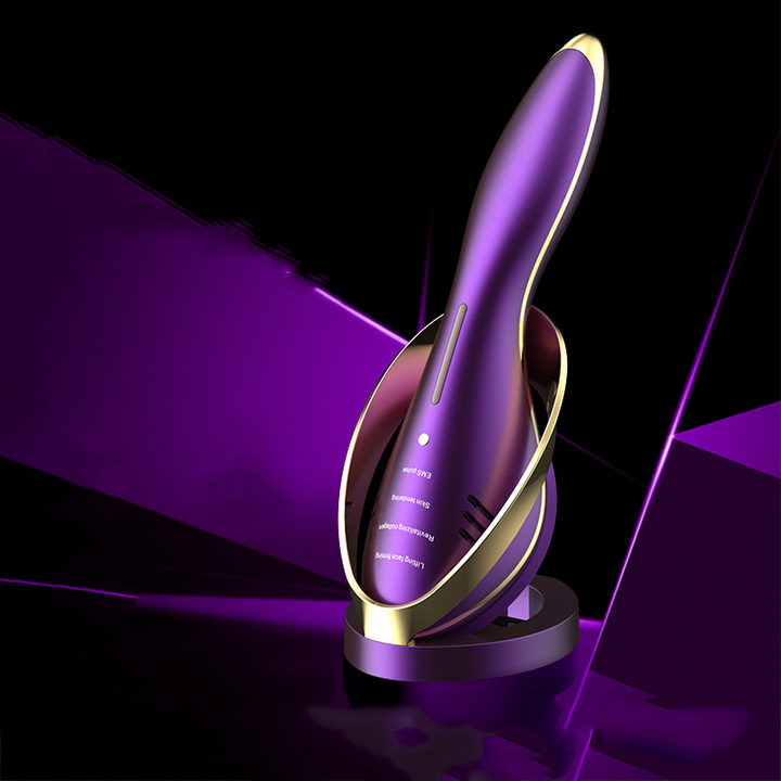 Purple and gold Skin Revive facial massager with matching charging stand against a purple backdrop.