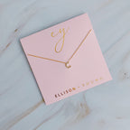 Gold initial C pendant necklace on a pink card with gold branding.