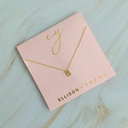 Gold initial B pendant necklace on a pink card with "ELLISON + YOUNG".