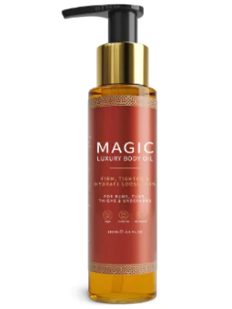 A tall amber glass pump bottle of Magic Luxury Body Oil with a red label and gold trim.