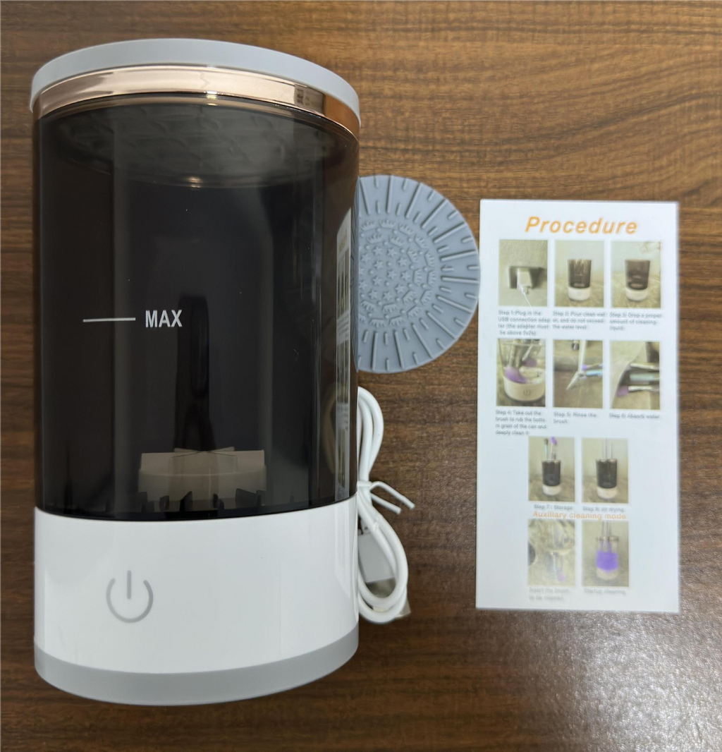A white and dark grey electric makeup brush cleaner with a power button, a silicone mat, and instructions.