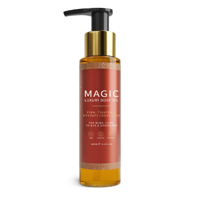 A tall, clear amber bottle of body oil with a gold and black pump dispenser and a red label.