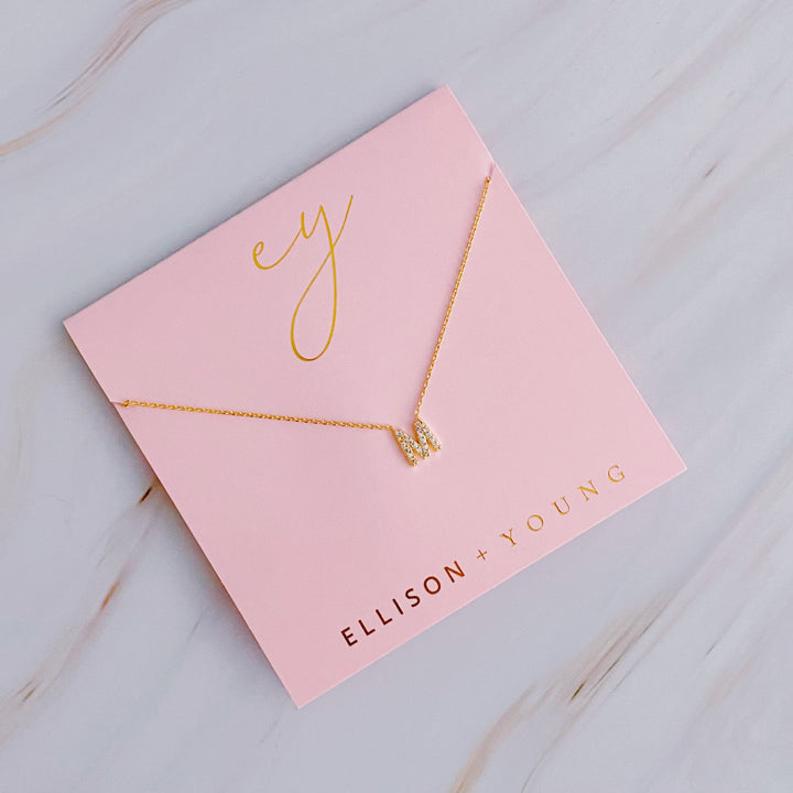 Gold initial pendant necklace on pink card with "ELLISON + YOUNG" and "ey" in gold lettering.