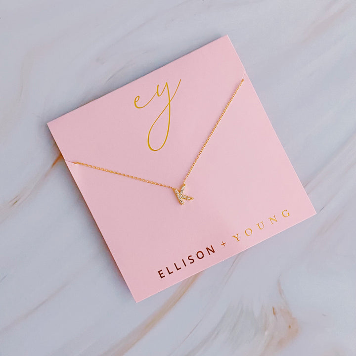Gold initial K pendant necklace on a pink card with gold lettering and brand logo.