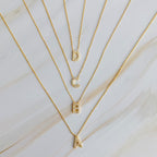 Four gold initial pendant necklaces with crystal-encrusted letters A, B, C, and D.