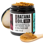 Open jar of brown, grainy batana hair oil with a wooden spoon holding a scoop in front.